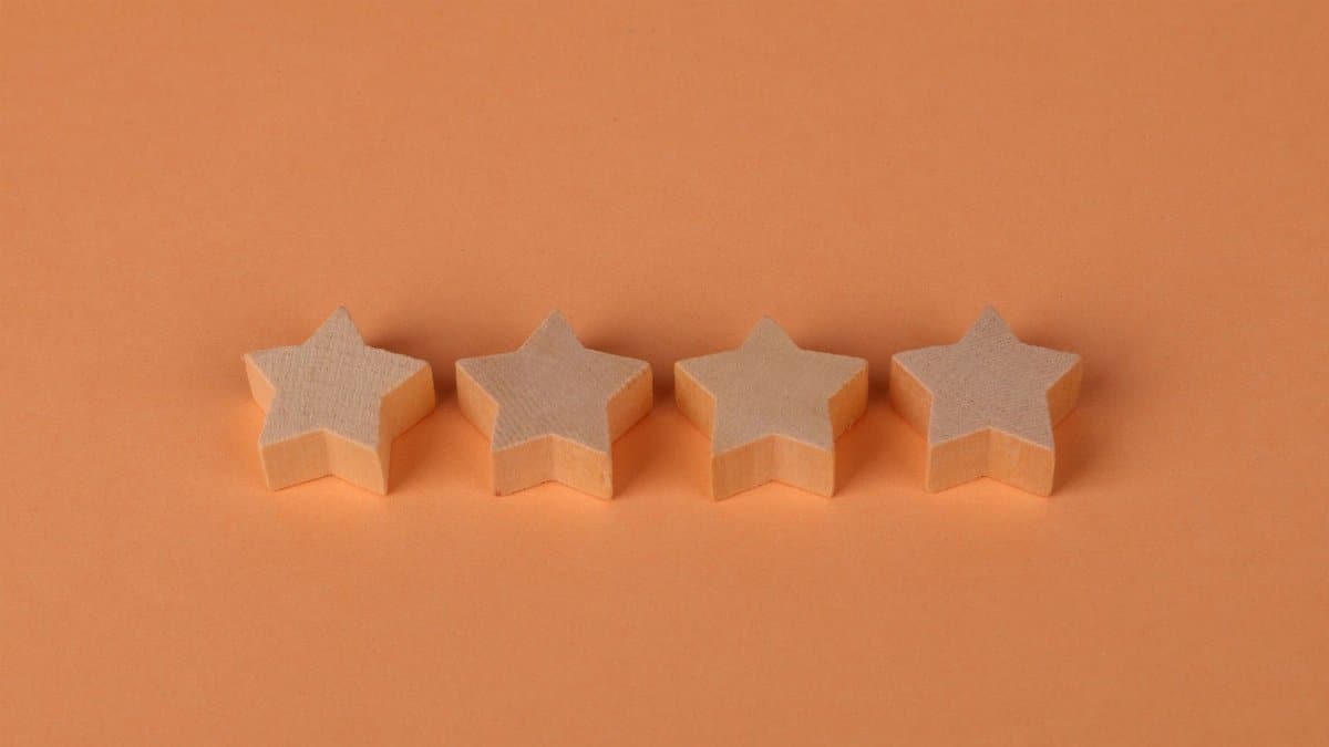 Four wooden star shaped blocks aligned on a plain orange surface, offering minimalist design.