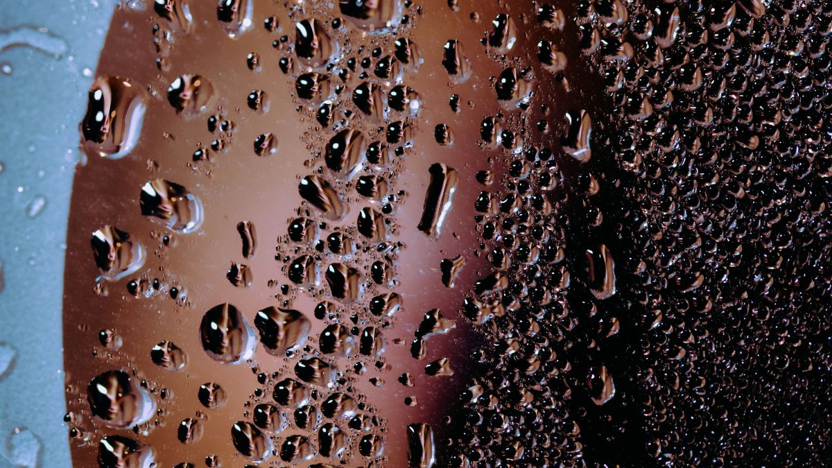 Abstract background of wet glass surface with splashed clean water drops in daylight