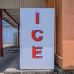 Outdoor ice machine with bright signage in Houston, TX on a sunny day.