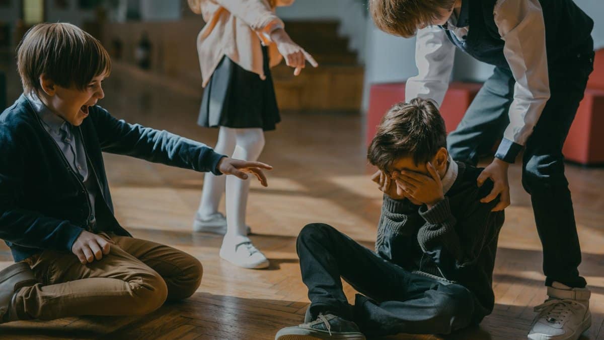 Group of kids bullying another child at school, signaling peer pressure and harassment.