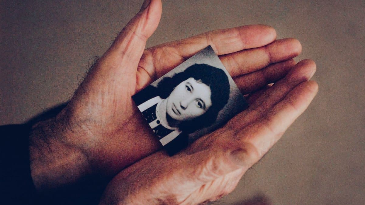 Close-up of hands gently holding an old black and white photo, evoking nostalgia and memories.