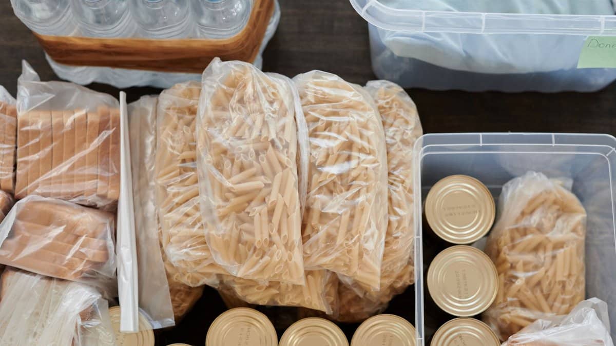 Aerial shot of pantry essentials including pasta, canned food, and bread packaged in plastic bags.