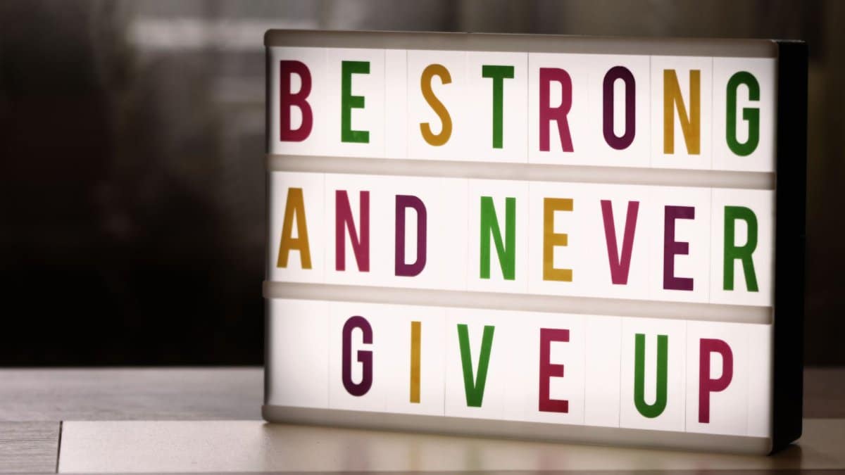 Inspirational lightbox displaying the motivational quote 'Be Strong and Never Give Up' indoors.