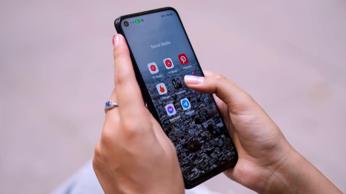 Close-up of hands holding a smartphone displaying social media apps, emphasizing digital connectivity.