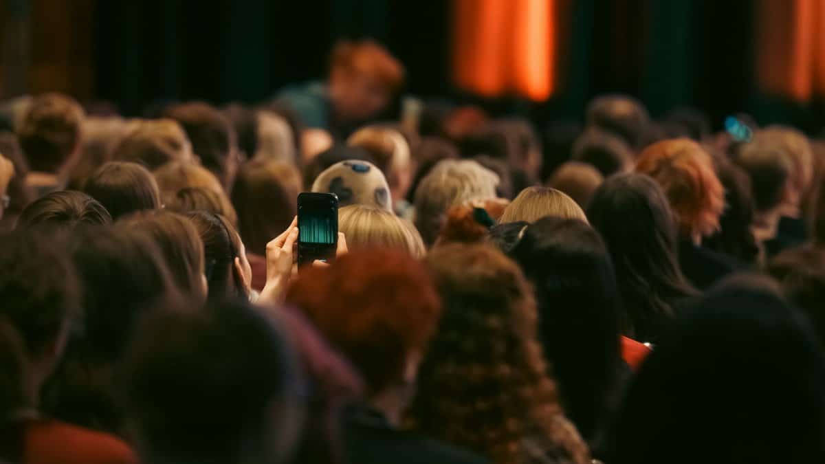 A smartphone captures a performance in a vibrant, crowded concert setting.