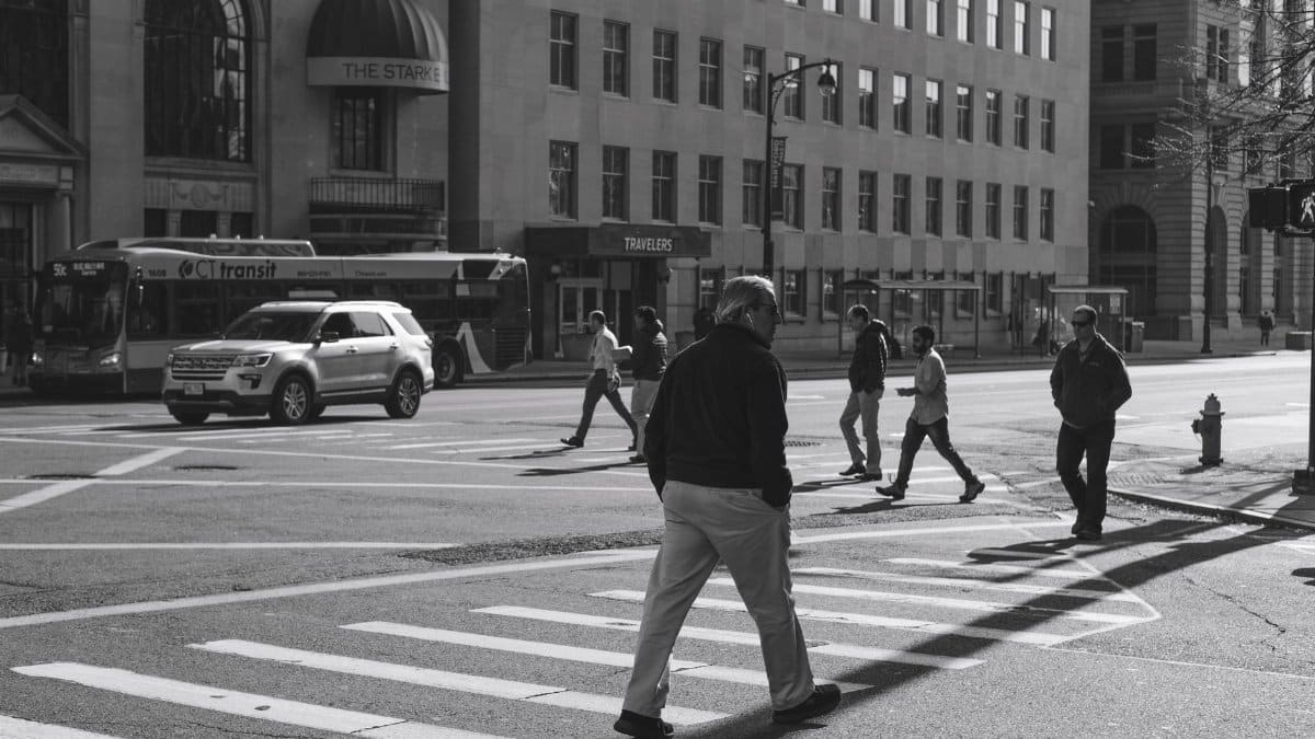 Black-and-white city scene with pedestrians crossing a street.