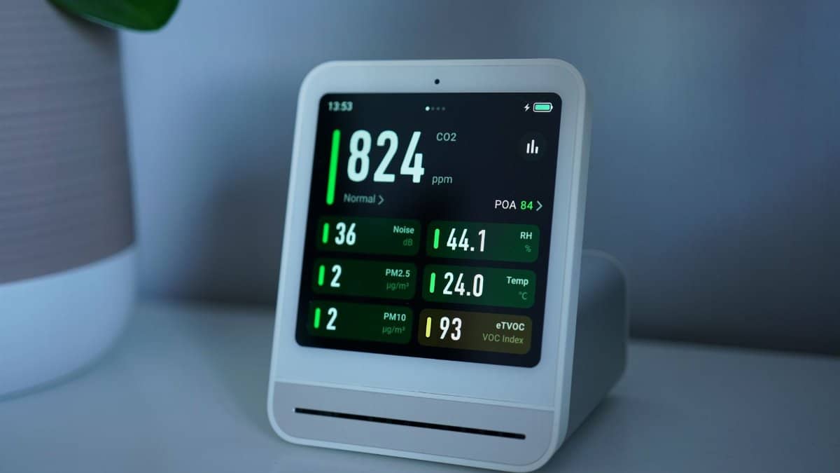 Close-up of a digital air quality monitor displaying CO2, PM2.5, and temperature readings.