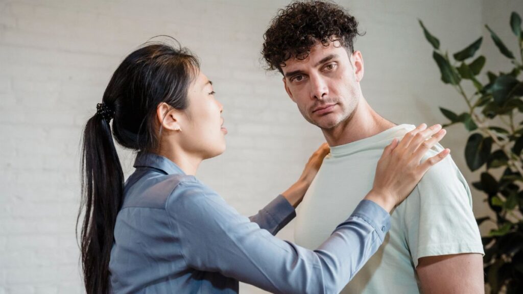 Man and woman engaging in a serious discussion indoors, expressing emotions.