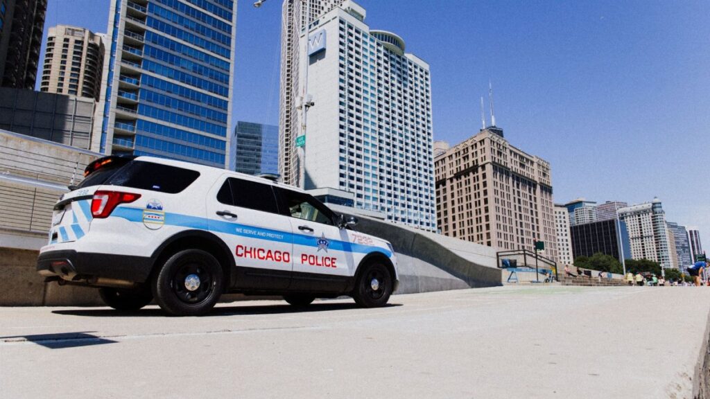 A Chicago Police SUV parked downtown against a skyline backdrop on a clear day.