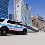 A Chicago Police SUV parked downtown against a skyline backdrop on a clear day.