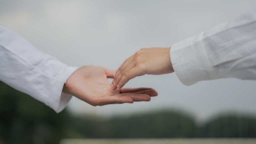 A symbolic image of two hands reaching out for connection and cooperation outdoors.