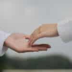 A symbolic image of two hands reaching out for connection and cooperation outdoors.