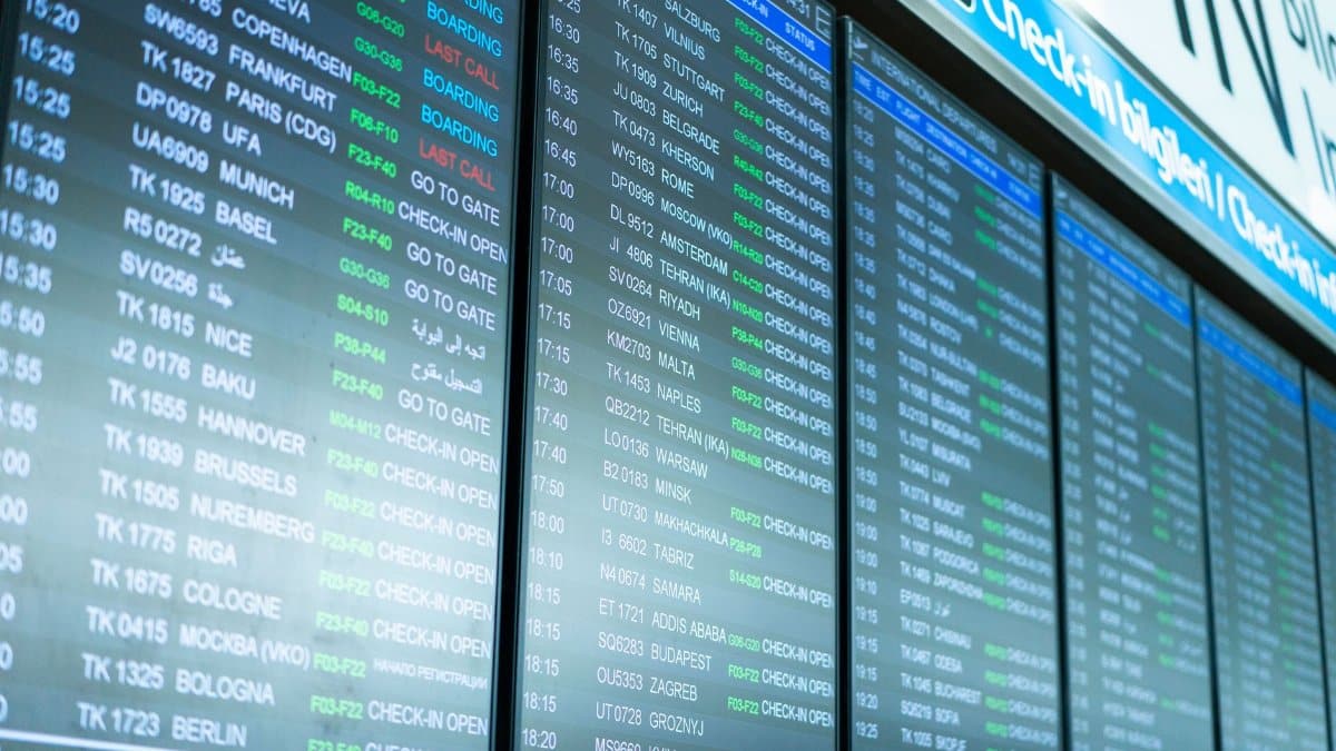 Digital screens display flight information and schedules at an airport terminal.