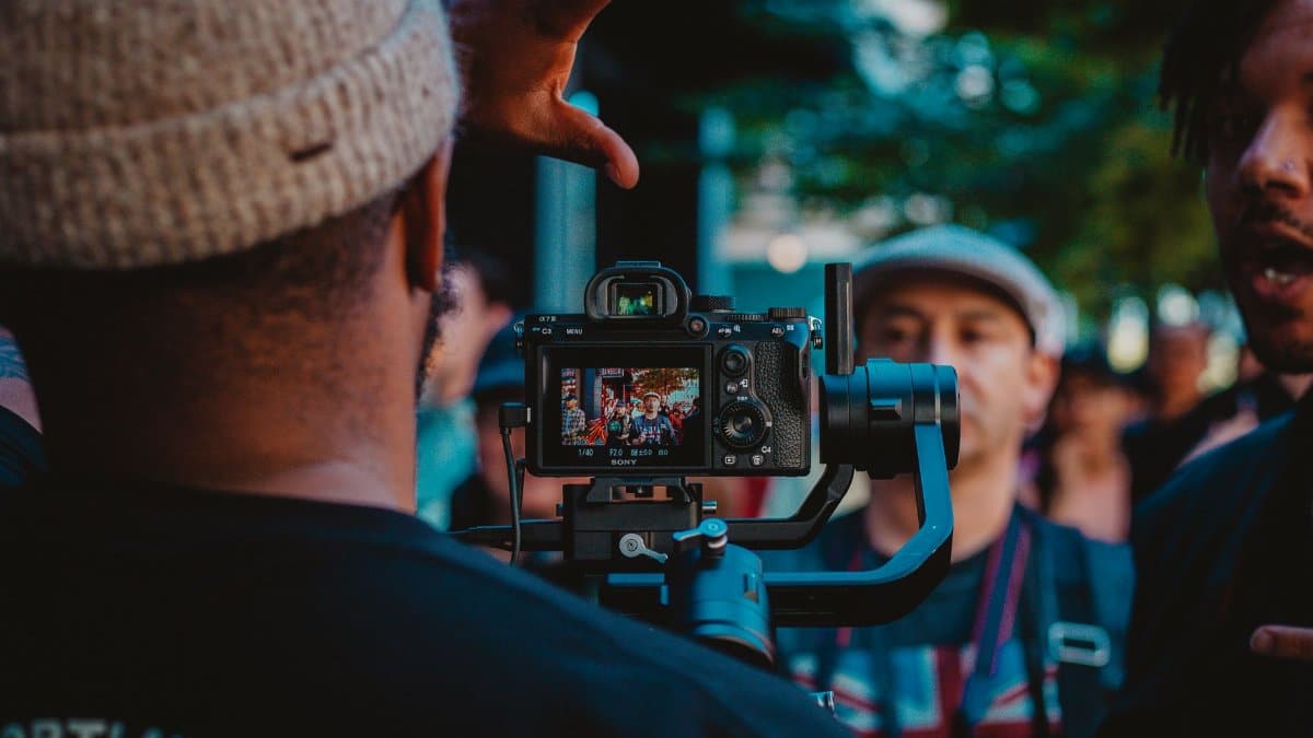 Photographer capturing a lively crowd with a DSLR camera at a street event.