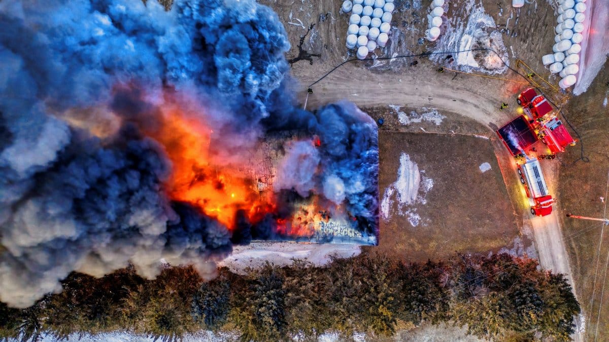 Dramatic aerial shot of a building on fire with firefighters battling the blaze.