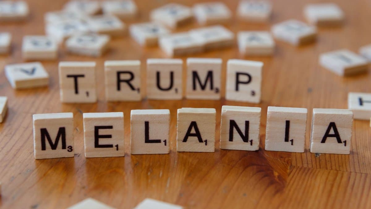Wooden tiles arranged with letters spelling 'TRUMP' and 'MELANIA' on a table.