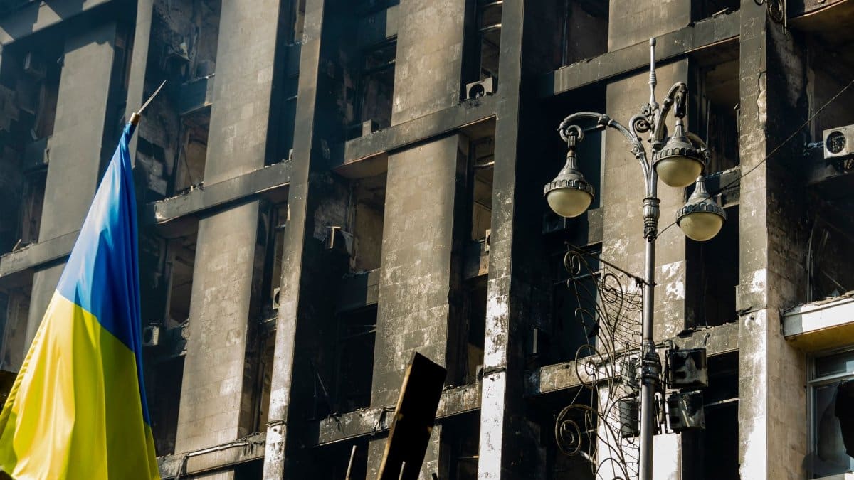 A damaged building in Kyiv, Ukraine with the Ukrainian flag displayed prominently.