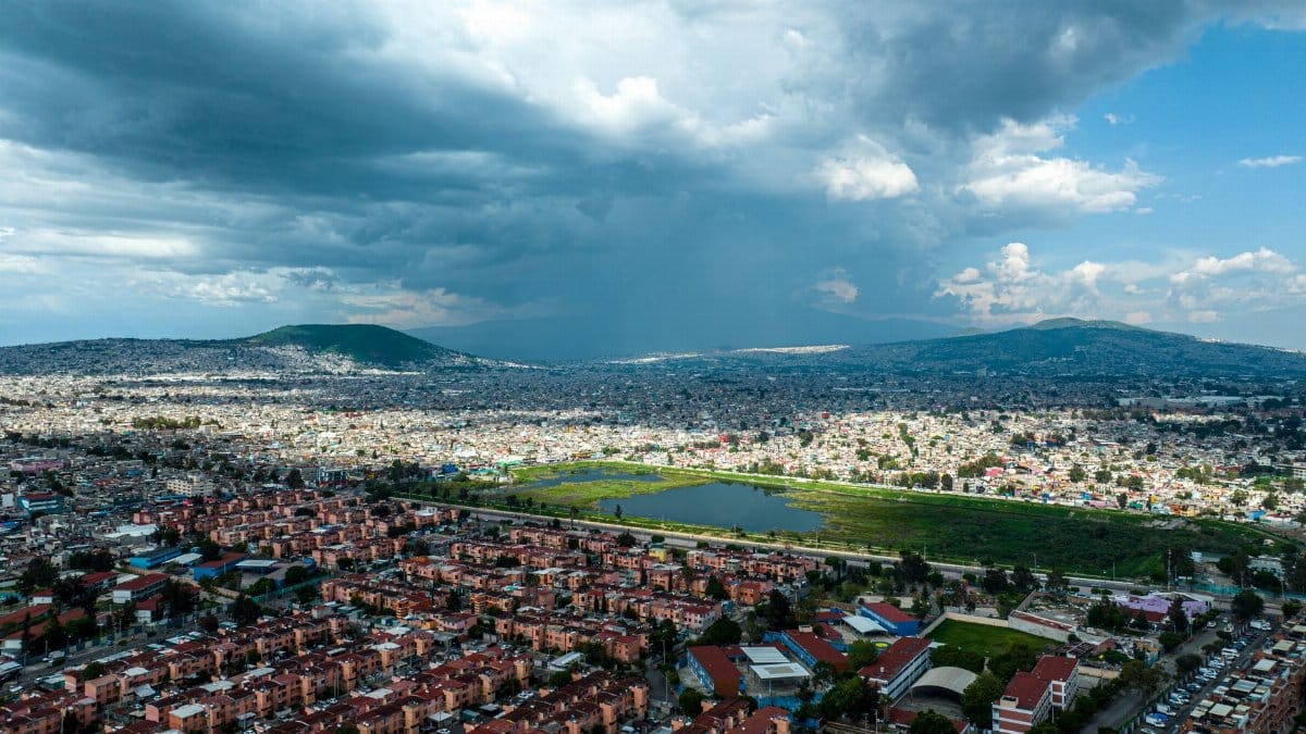 A breathtaking aerial view of a city under a dramatic, stormy sky. Dense urban layout surrounded by mountains.