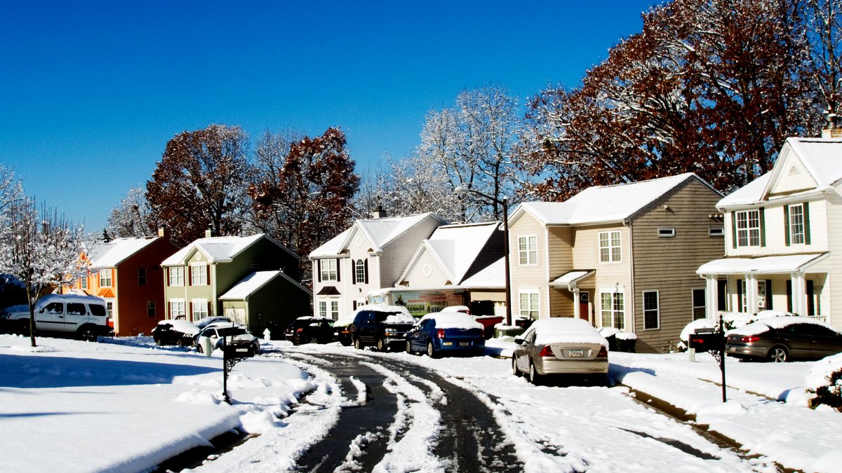 A picturesque snowy street view in Austell, Georgia with colorful houses and a clear blue sky.