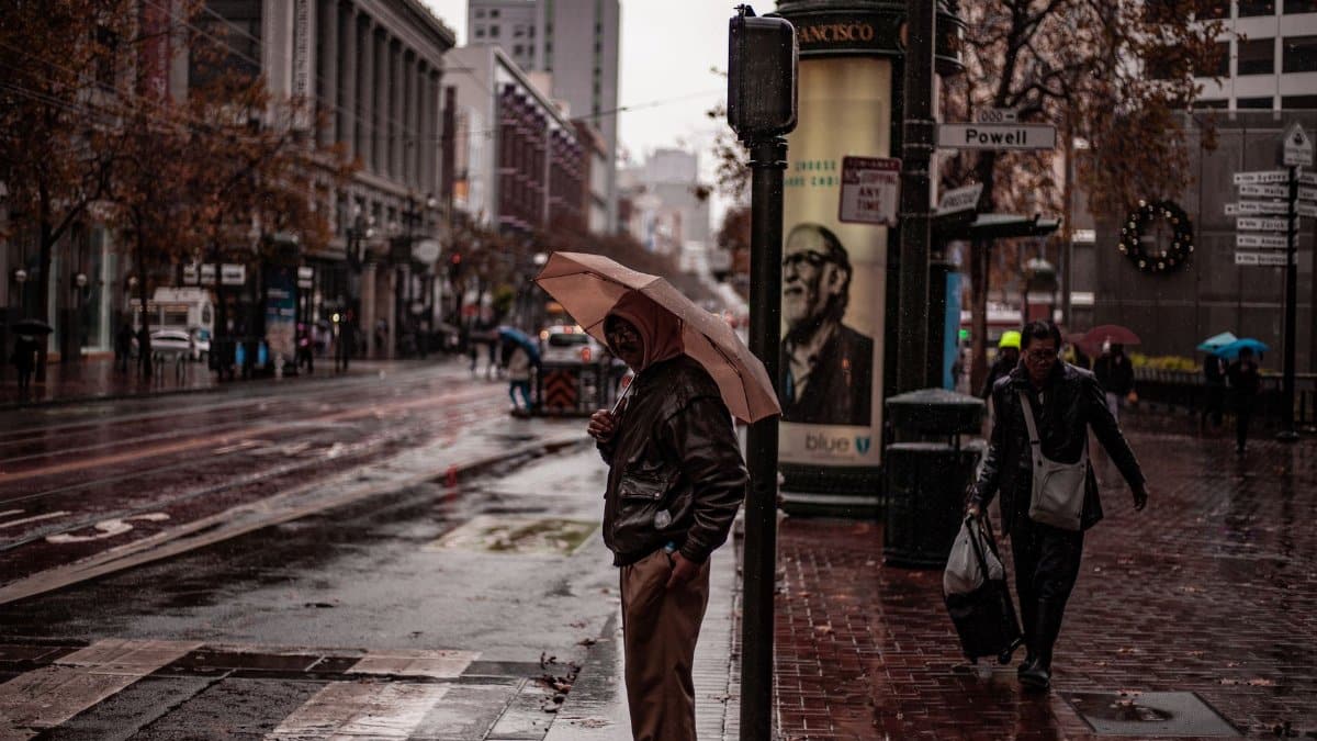 A rainy day in San Francisco with people walking along Powell Street holding umbrellas.