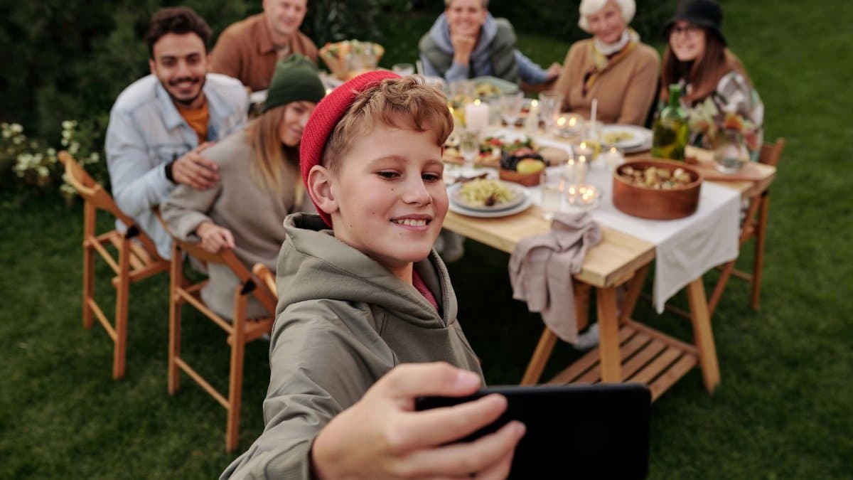Cheerful family taking a selfie during an outdoor garden dinner party.
