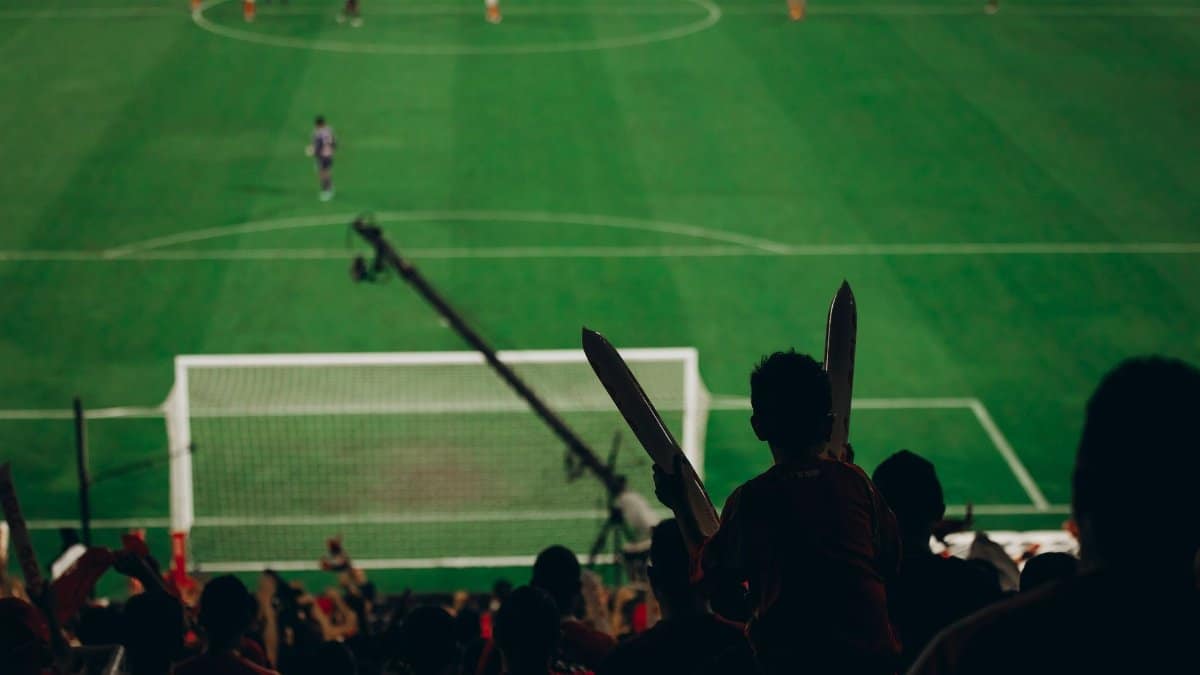 Fans cheer during a thrilling football match as the players engage intensely on the field.