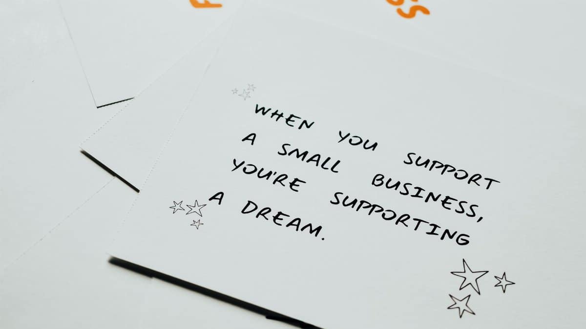 Motivational note on white paper about supporting small businesses with decorative stars.
