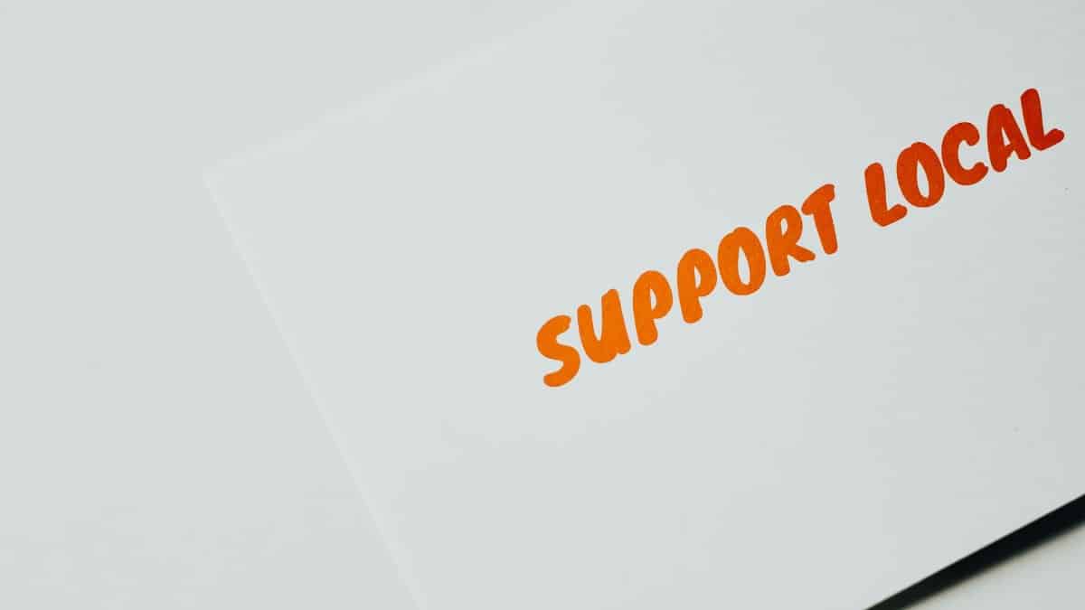 Close-up of 'Support Local' message on white paper, encouraging local support.