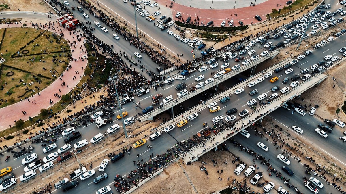 A dynamic aerial shot capturing heavy traffic flow on a multilayered highway in Iraq, showing urban life.