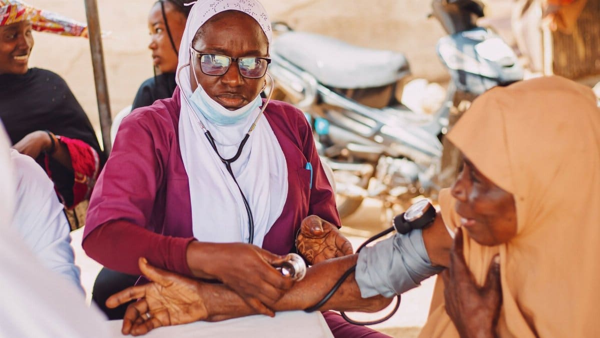 Outdoor portrait of healthcare professional attending to a patient, promoting community wellness in Kaduna, Nigeria.