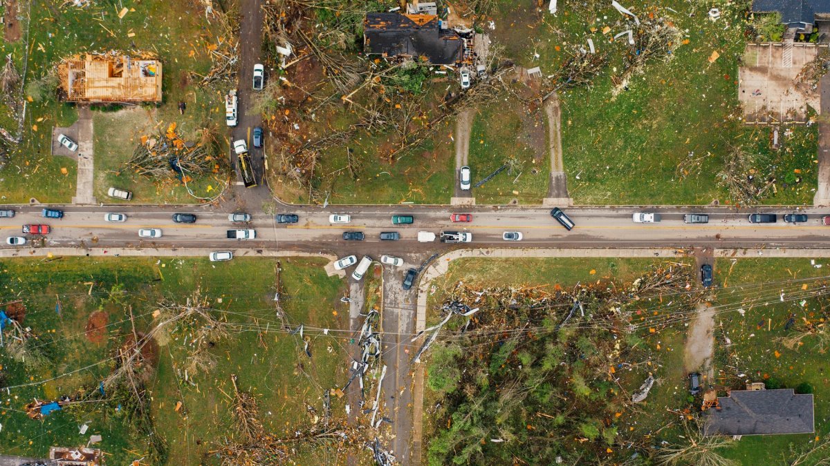 Drone view of small neighborhood cottages destroyed by hurricane near windthrown trees and electricity power lines along narrow road
