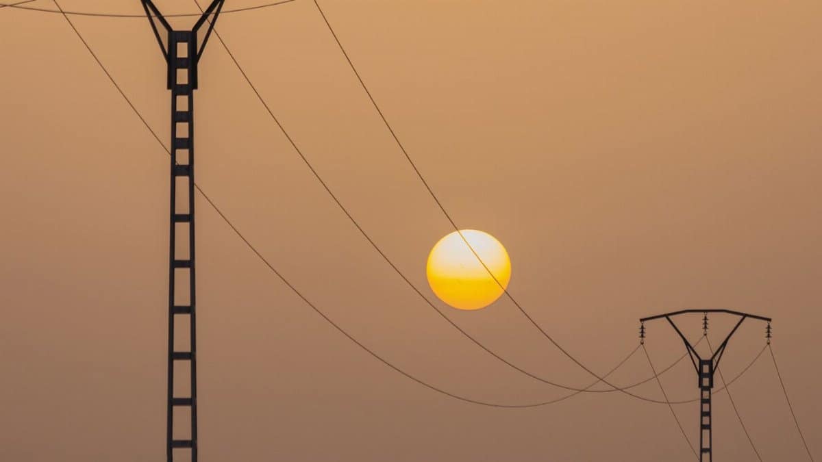 Silhouette of power lines against a vibrant sunset sky in El Menia, Algeria.