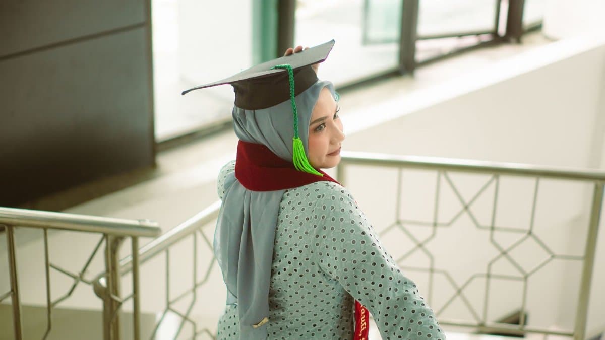A young woman in a hijab wears a graduation cap, symbolizing success and achievement.