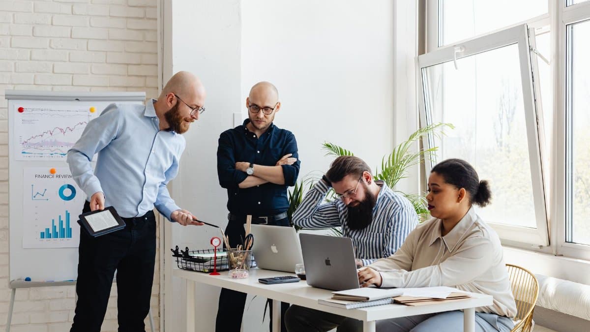 A diverse team discusses strategy in a modern office setting with laptops and charts.