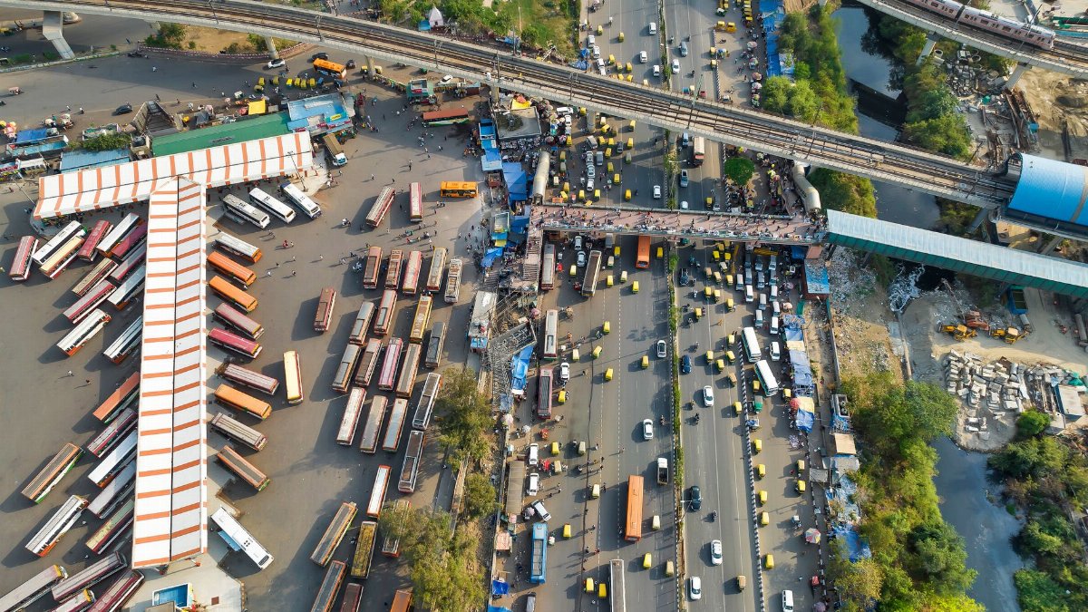 Aerial view of a busy bus station and roadway with vibrant urban activity.