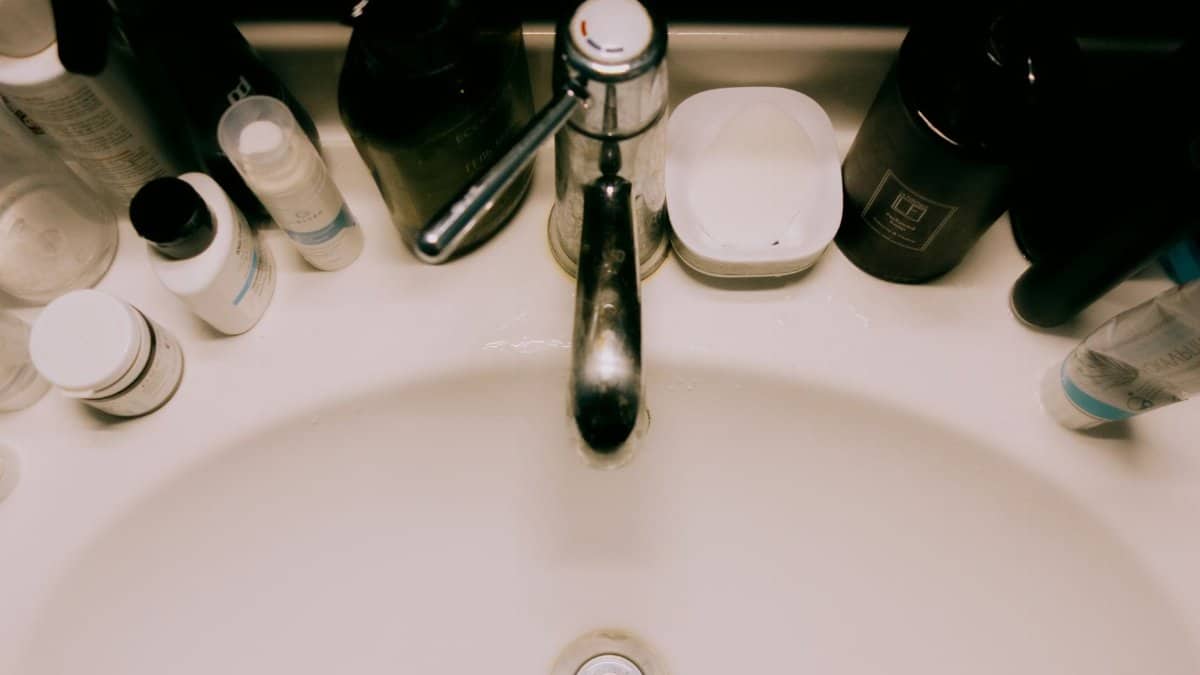 Overhead view of a bathroom sink surrounded by various toiletries, offering a modern minimalist aesthetic.