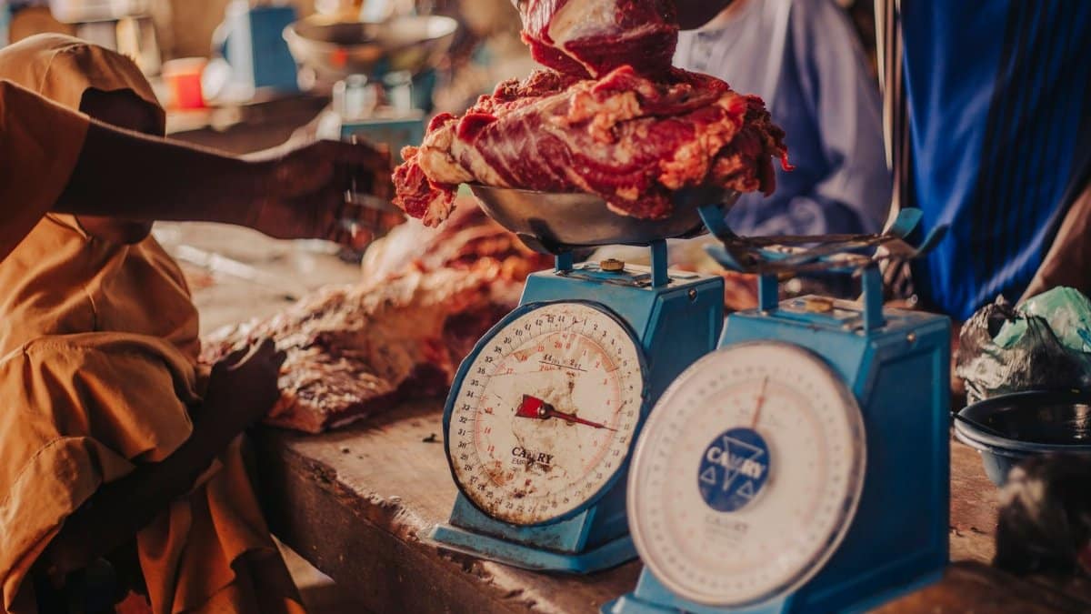 Fresh meat being weighed in a vibrant local market setting.