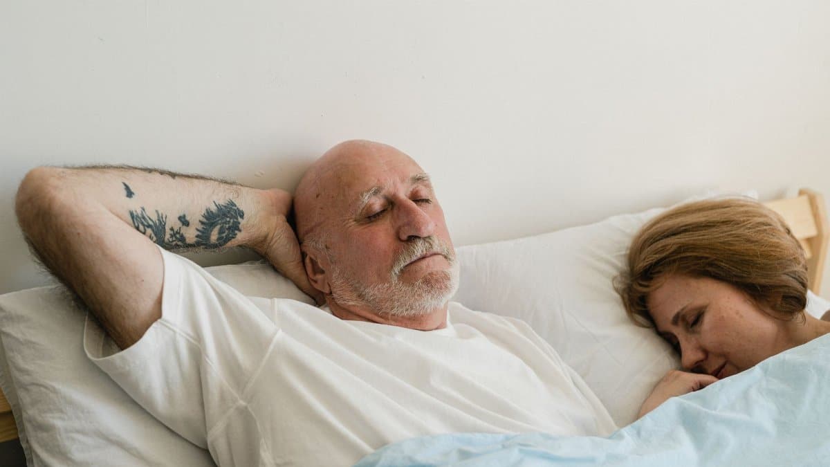 Peaceful elderly couple sleeping together in bed, showing relaxation and comfort.