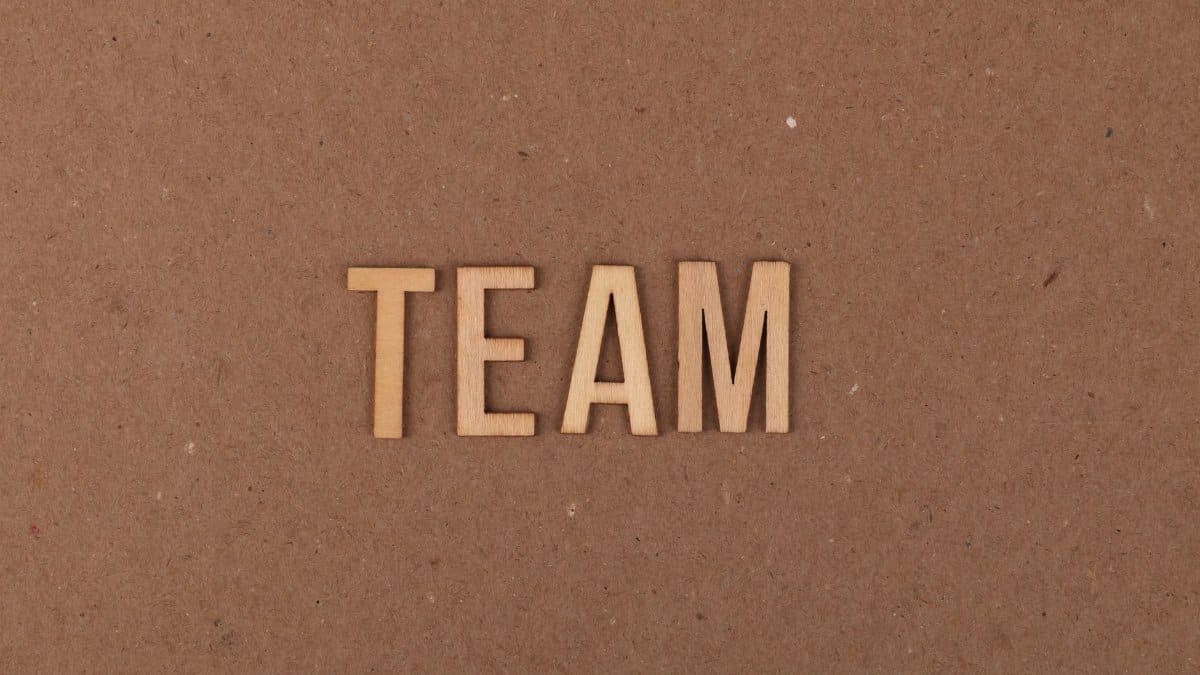 Wooden letters on a brown background spelling 'TEAM' symbolize teamwork and collaboration.