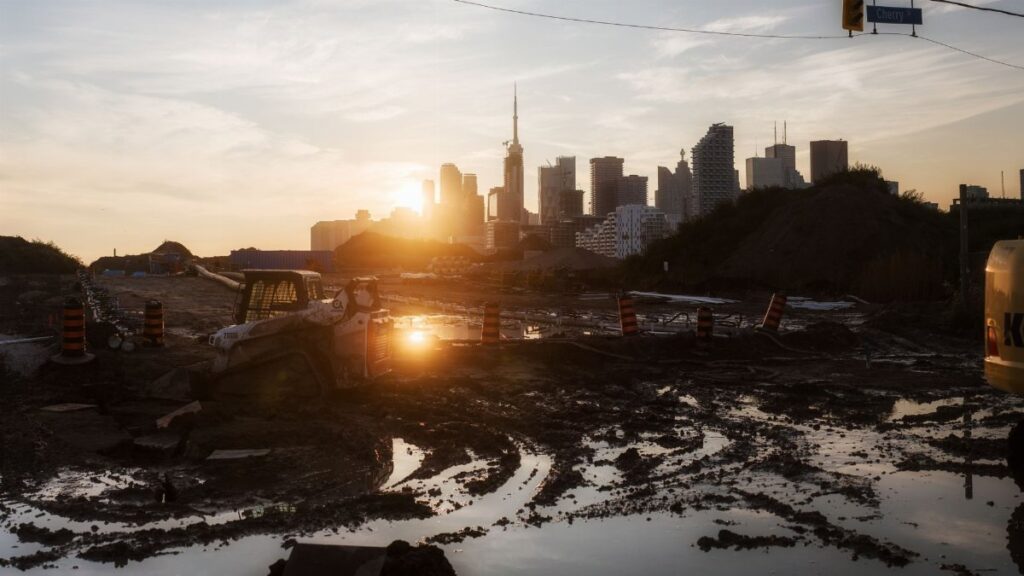 A tractor at a construction site with city skyline and sunset background, reflecting urban development.