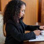 Professional female lawyer with curly hair reviewing legal documents in an office setting.