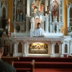 A priest conducts mass at a beautifully decorated church altar, engaging the congregation.