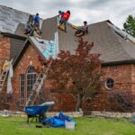 Roofers working on brick home in Allen, Texas, addressing shingles and roofing materials.