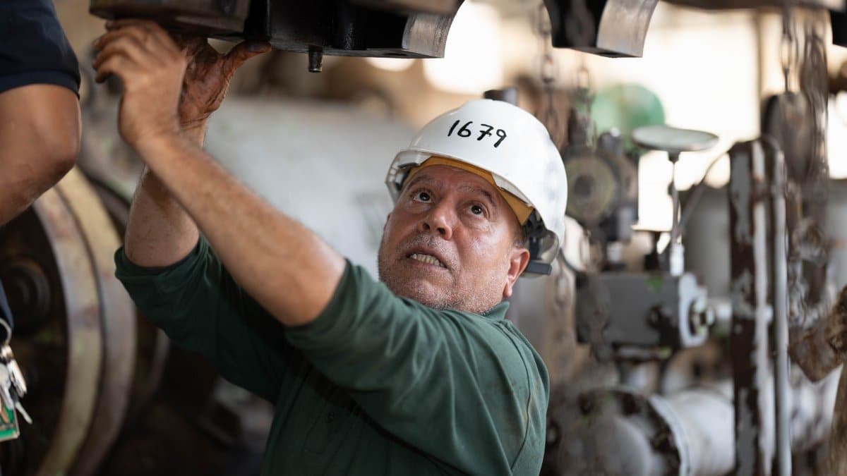 Engineer examines heavy machinery in an industrial site, showcasing technical expertise.