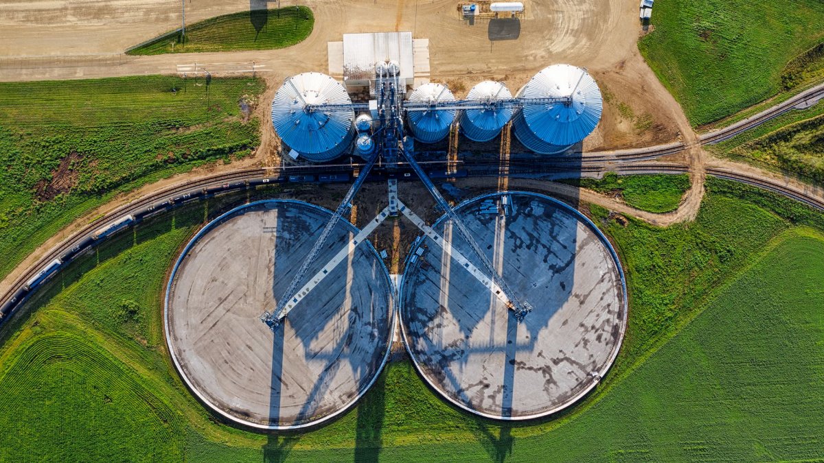 Drone shot capturing modern silos in a vibrant green field in Randolph, MN.