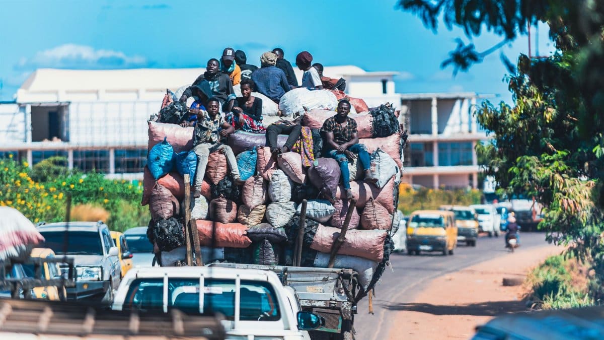 A heavily loaded truck with people and goods navigating a busy street in Lubumbashi, showcasing urban mobility challenges.