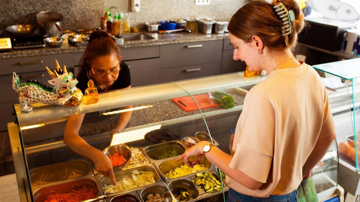 Woman choosing fresh vegetables at a New York City food bar counter.