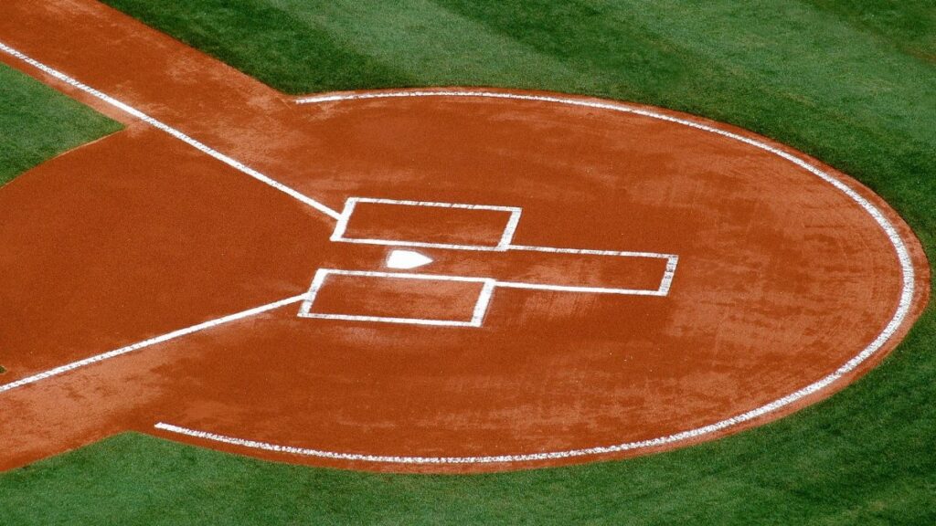 A top-down view of a baseball field's home plate area on a sunny day.