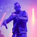 Vibrant live rap concert with performer on stage under colorful lights.