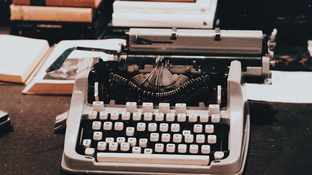 Close-up of an antique typewriter on a desk surrounded by books, evoking a classic retro style.